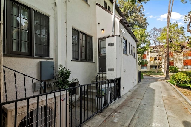 view of side of property with stucco siding and fence