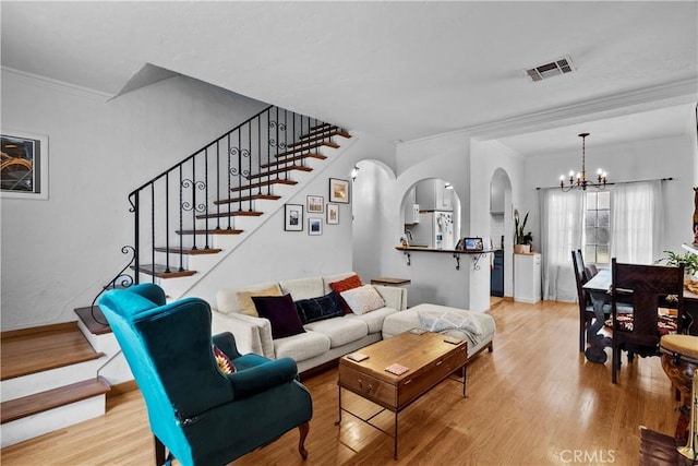 living room featuring arched walkways, visible vents, a chandelier, and light wood-style floors