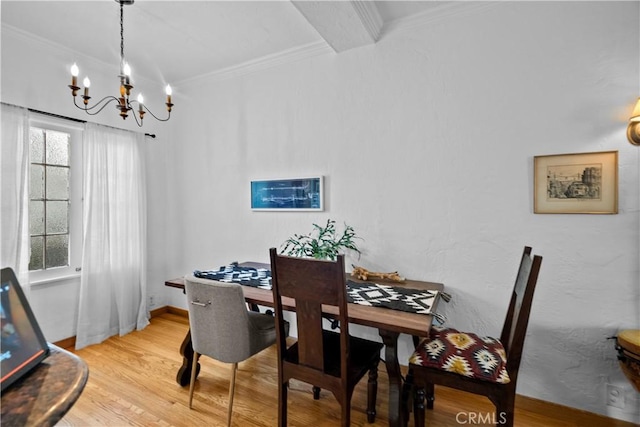 dining space featuring light wood finished floors, baseboards, ornamental molding, and an inviting chandelier