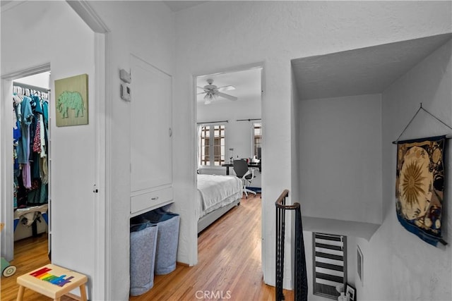 bedroom featuring a textured ceiling, a spacious closet, and light wood finished floors