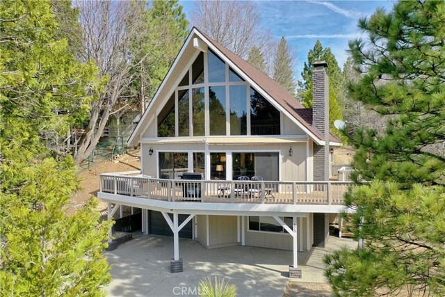675 Grass Valley Rd, Lake Arrowhead, CA 92352 - back of property featuring a deck, driveway, a chimney, and a garage