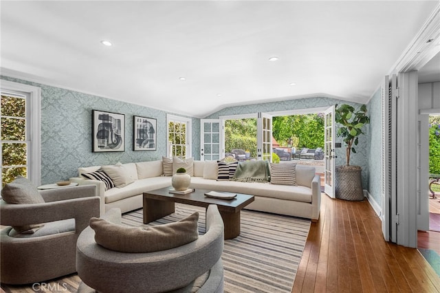 living area with wood-type flooring, vaulted ceiling, and wallpapered walls