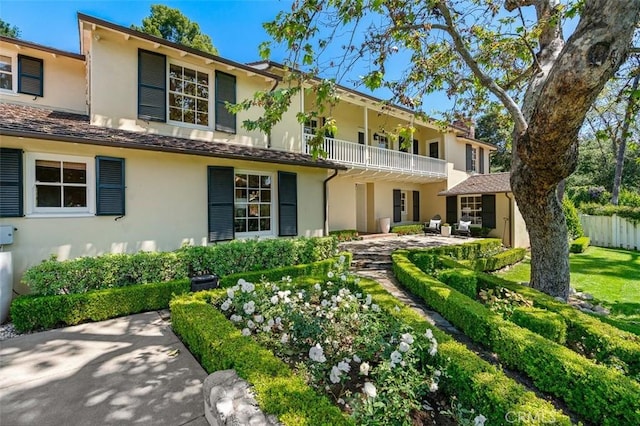 view of front of home with a patio, fence, a balcony, and stucco siding