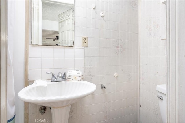 half bathroom featuring tasteful backsplash, tile walls, and toilet