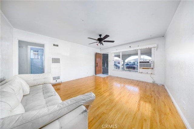living area featuring ceiling fan, a healthy amount of sunlight, a heating unit, and wood finished floors