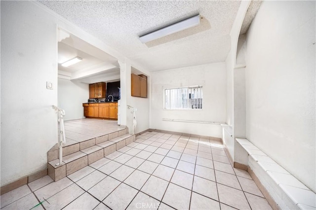 unfurnished living room with a textured ceiling and light tile patterned floors