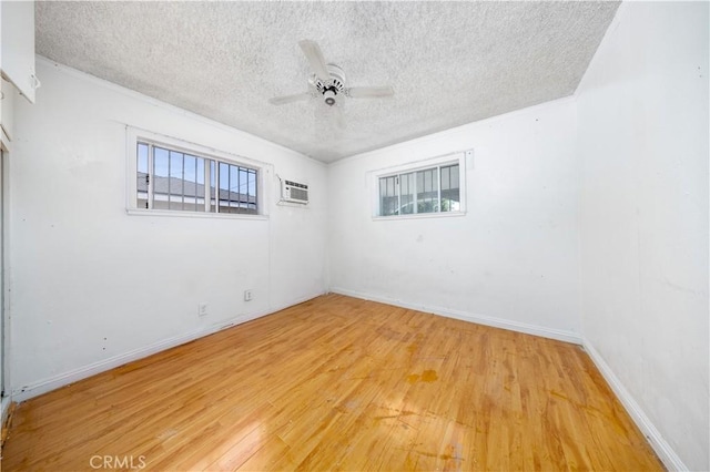 spare room with light wood-type flooring, baseboards, a wall mounted AC, a textured ceiling, and ceiling fan