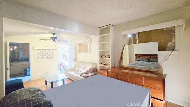 bedroom featuring ensuite bath, wood finished floors, and a textured ceiling