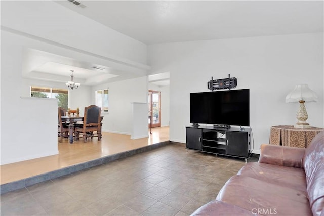 living area featuring an inviting chandelier, a raised ceiling, and baseboards
