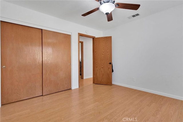 unfurnished bedroom featuring baseboards, light wood-style floors, visible vents, a ceiling fan, and a closet