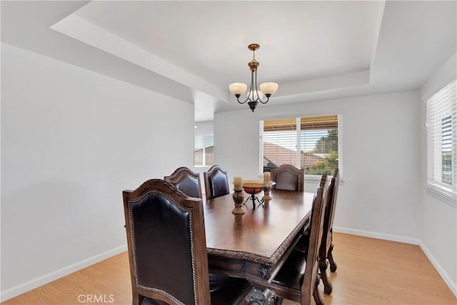 dining space with a tray ceiling, baseboards, plenty of natural light, and light wood-style flooring