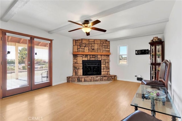 living room featuring plenty of natural light, beam ceiling, wood finished floors, and ceiling fan