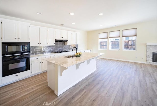 32706 Blue Mist Way, Wildomar, CA 92595 - kitchen with a sink, black appliances, light wood-style flooring, white cabinets, and light stone countertops
