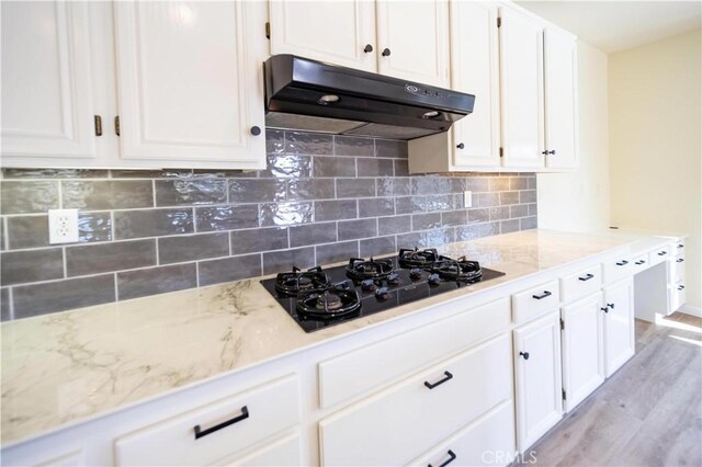 32706 Blue Mist Way, Wildomar, CA 92595 - kitchen with under cabinet range hood, light stone counters, black gas stovetop, and white cabinetry