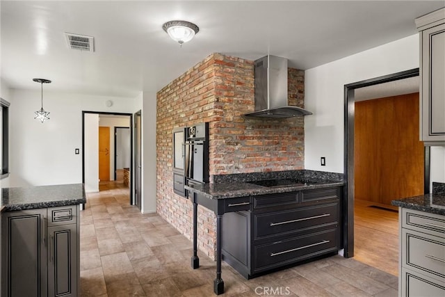kitchen with visible vents, wall chimney exhaust hood, dark stone countertops, dark cabinets, and black appliances