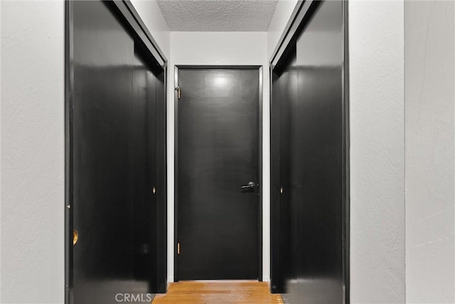 hall featuring light wood finished floors and a textured ceiling