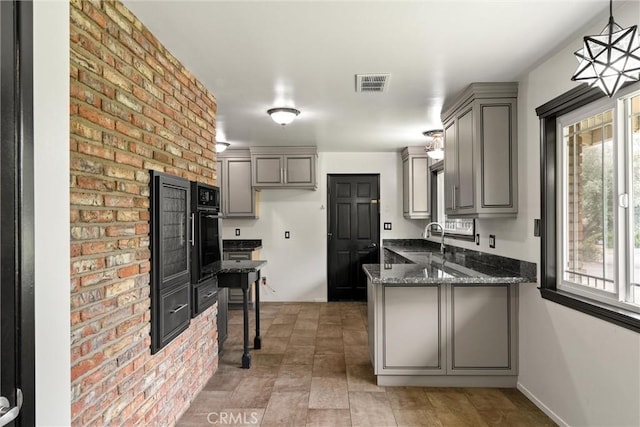 kitchen with gray cabinetry, black oven, visible vents, and a peninsula