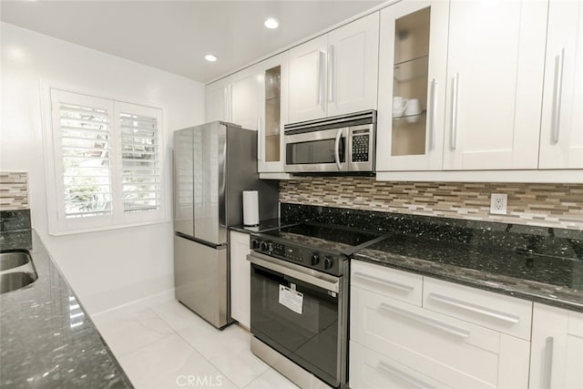 kitchen with backsplash, white cabinetry, appliances with stainless steel finishes, and dark stone counters