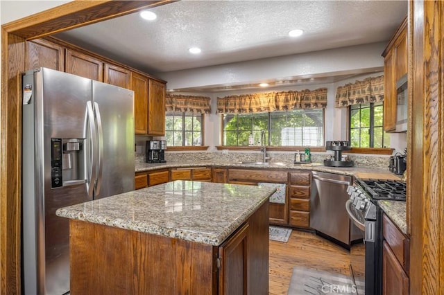 kitchen featuring a textured ceiling, appliances with stainless steel finishes, a sink, and light wood-type flooring