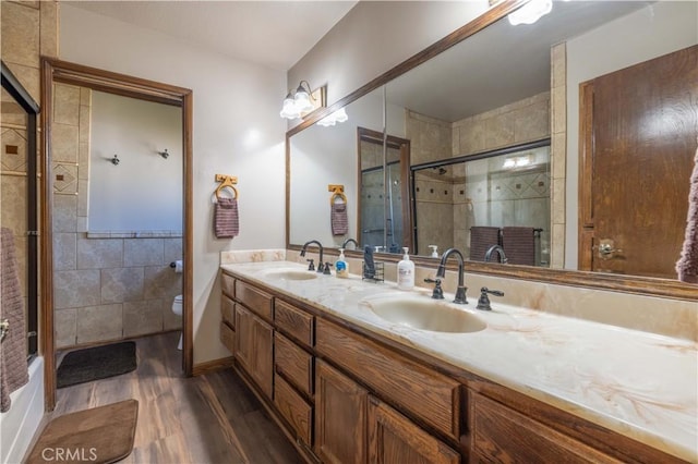 full bathroom with double vanity, a sink, wood finished floors, and tiled shower
