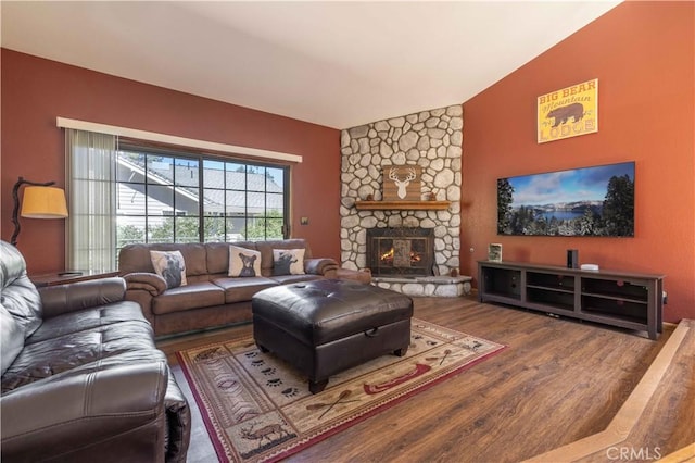 living area with a stone fireplace, vaulted ceiling, and wood finished floors