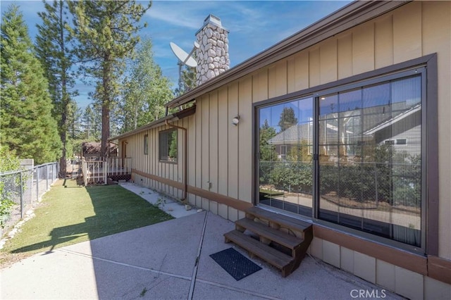 view of side of property with a yard, a chimney, a fenced backyard, and a patio area