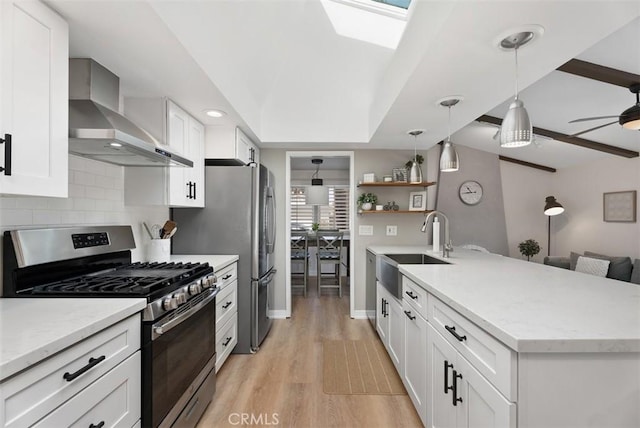 9871 Silver Strand Dr, Huntington Beach, CA 92646 - kitchen with a peninsula, tasteful backsplash, appliances with stainless steel finishes, a sink, and wall chimney range hood