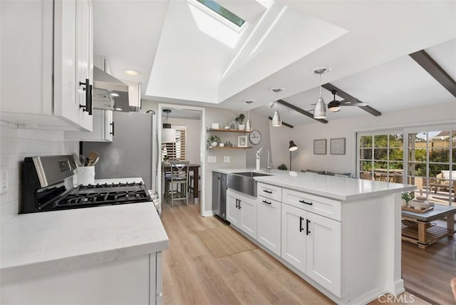 9871 Silver Strand Dr, Huntington Beach, CA 92646 - kitchen with a sink, a peninsula, light wood-type flooring, stainless steel appliances, and white cabinets