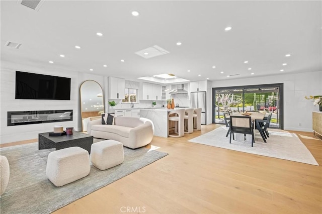 living room with light wood finished floors, visible vents, a large fireplace, and recessed lighting