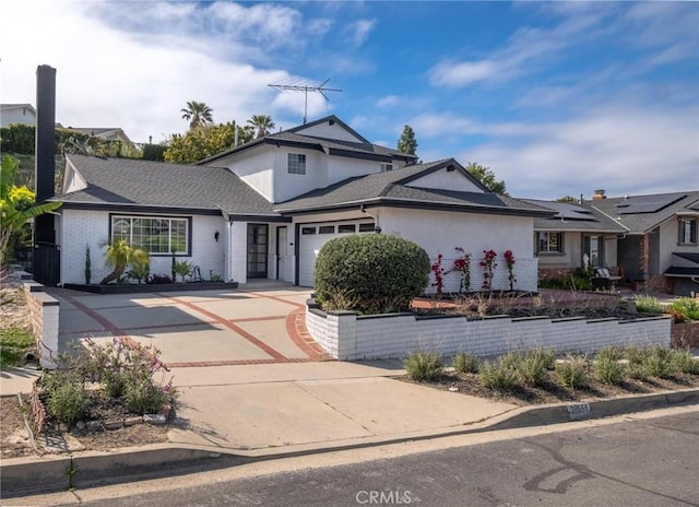 traditional home with stucco siding, an attached garage, driveway, brick siding, and a shingled roof