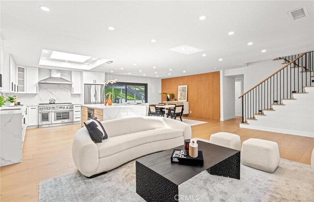living area featuring stairs, visible vents, light wood-style flooring, and recessed lighting