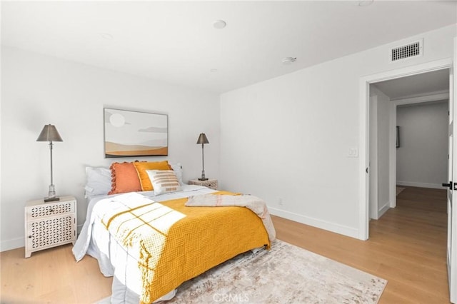 bedroom with baseboards, visible vents, and light wood-style floors