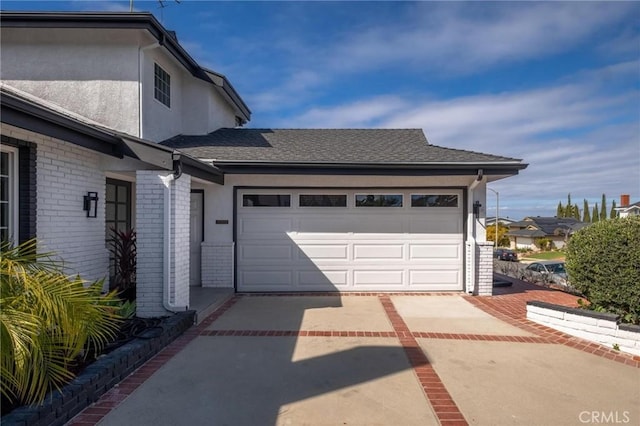 exterior space with stucco siding, driveway, brick siding, a garage, and a shingled roof