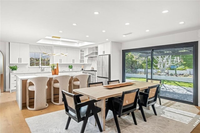 dining area featuring a tray ceiling, recessed lighting, and light wood-type flooring