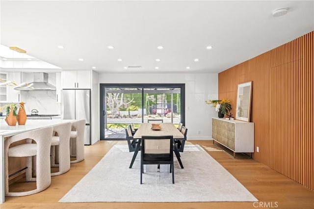 dining area featuring wooden walls, light wood-style floors, and recessed lighting