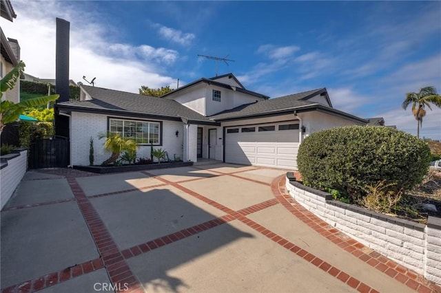 traditional home with a shingled roof, a garage, brick siding, and concrete driveway