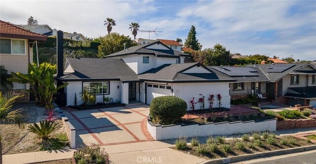 view of front of property featuring a garage, concrete driveway, and a residential view