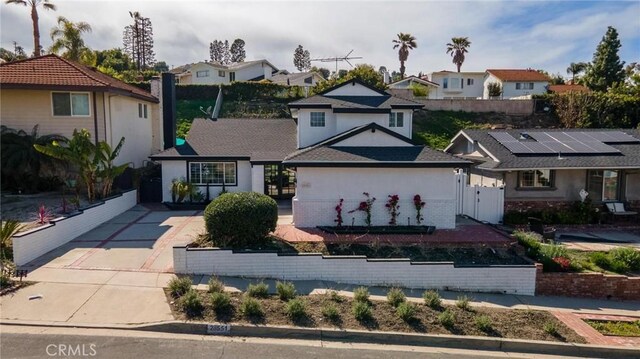 traditional-style home with concrete driveway, stucco siding, fence, a residential view, and a gate