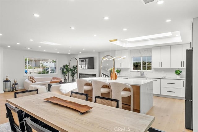 dining space featuring recessed lighting, a skylight, and light wood finished floors