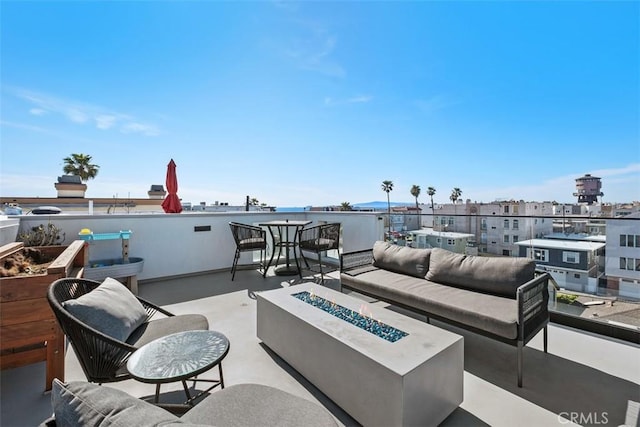 view of patio featuring a balcony, an outdoor living space with a fire pit, and a city view