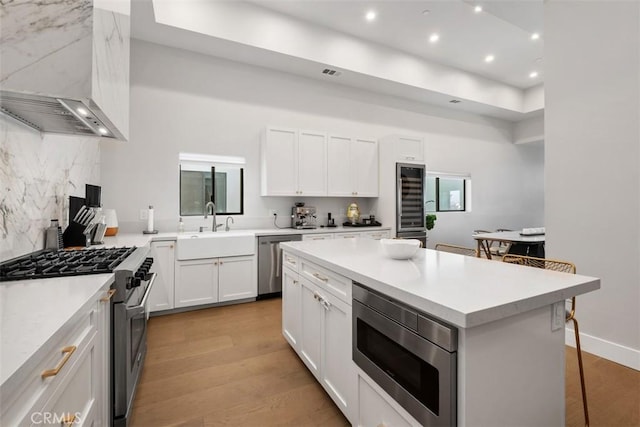 kitchen with wine cooler, light countertops, stainless steel appliances, and light wood-style floors