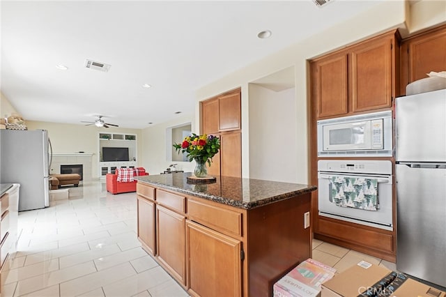 25445 Clovelly Ct, Moreno Valley, CA 92553 - kitchen featuring a glass covered fireplace, a center island, white appliances, visible vents, and ceiling fan