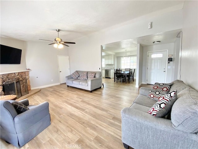 11031 Victor Ave, Hesperia, CA 92345 - living room featuring light wood-style flooring, a ceiling fan, baseboards, and a stone fireplace