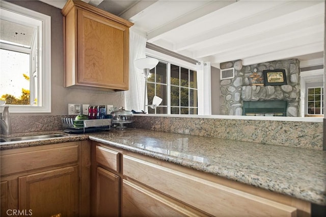 475 Woodsey Rd, Crestline, CA 92325 - kitchen featuring a sink, beam ceiling, visible vents, a stone fireplace, and brown cabinets