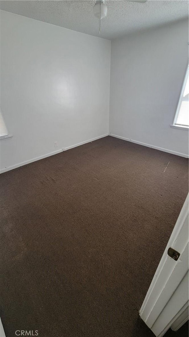 1640 Alameda St, Pomona, CA 91768 - empty room featuring a textured ceiling, dark colored carpet, and baseboards