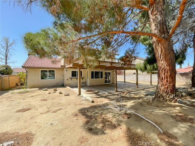 view of front of property featuring stucco siding, a patio area, a tile roof, and fence