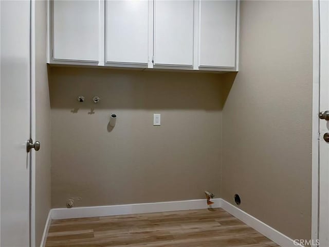 washroom with gas dryer hookup, cabinet space, light wood-style flooring, and baseboards