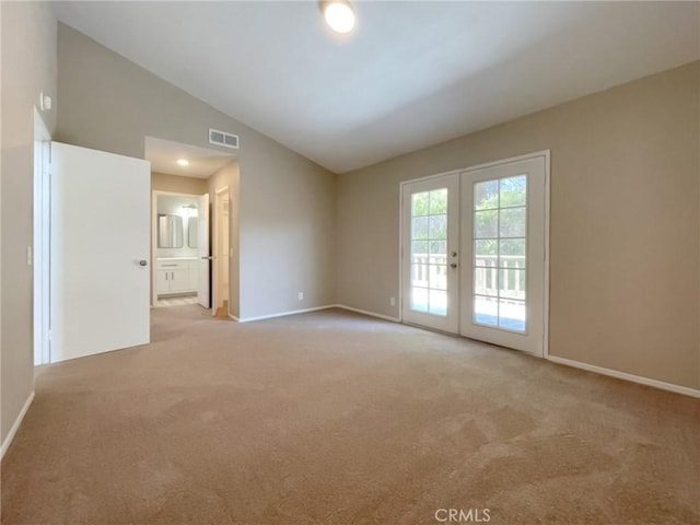 spare room featuring lofted ceiling, carpet, baseboards, and french doors