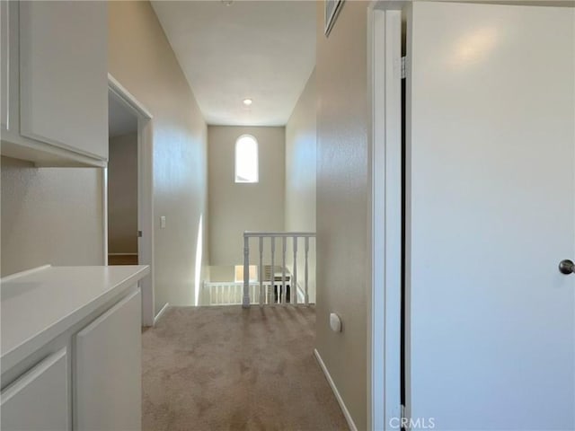 hall with light colored carpet, an upstairs landing, and baseboards