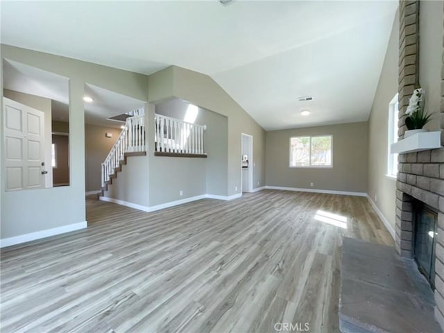 unfurnished living room with a fireplace, wood finished floors, baseboards, and lofted ceiling
